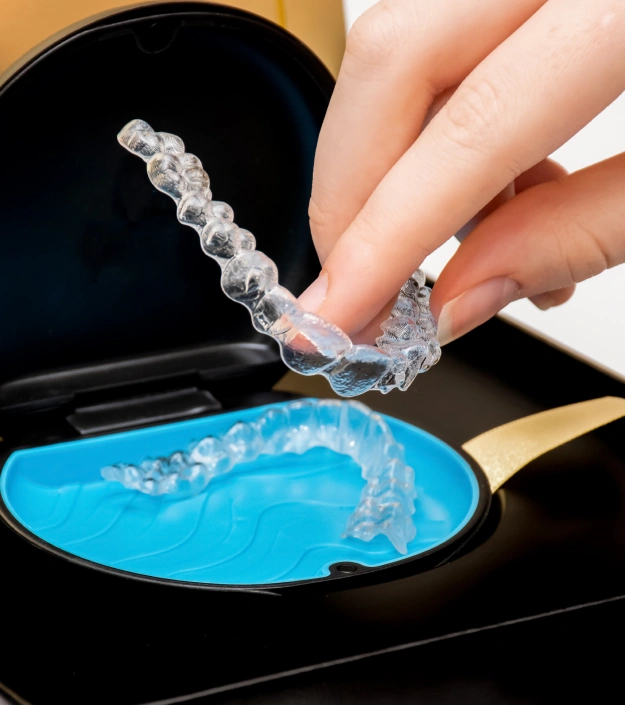 Clear Invisalign aligner being placed into a storage case for discreet teeth straightening treatment at Cariboo Choice Dental